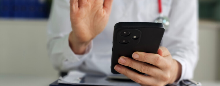 Doctor conducts telemedicine consultation while holding a smartphone in a modern medical office