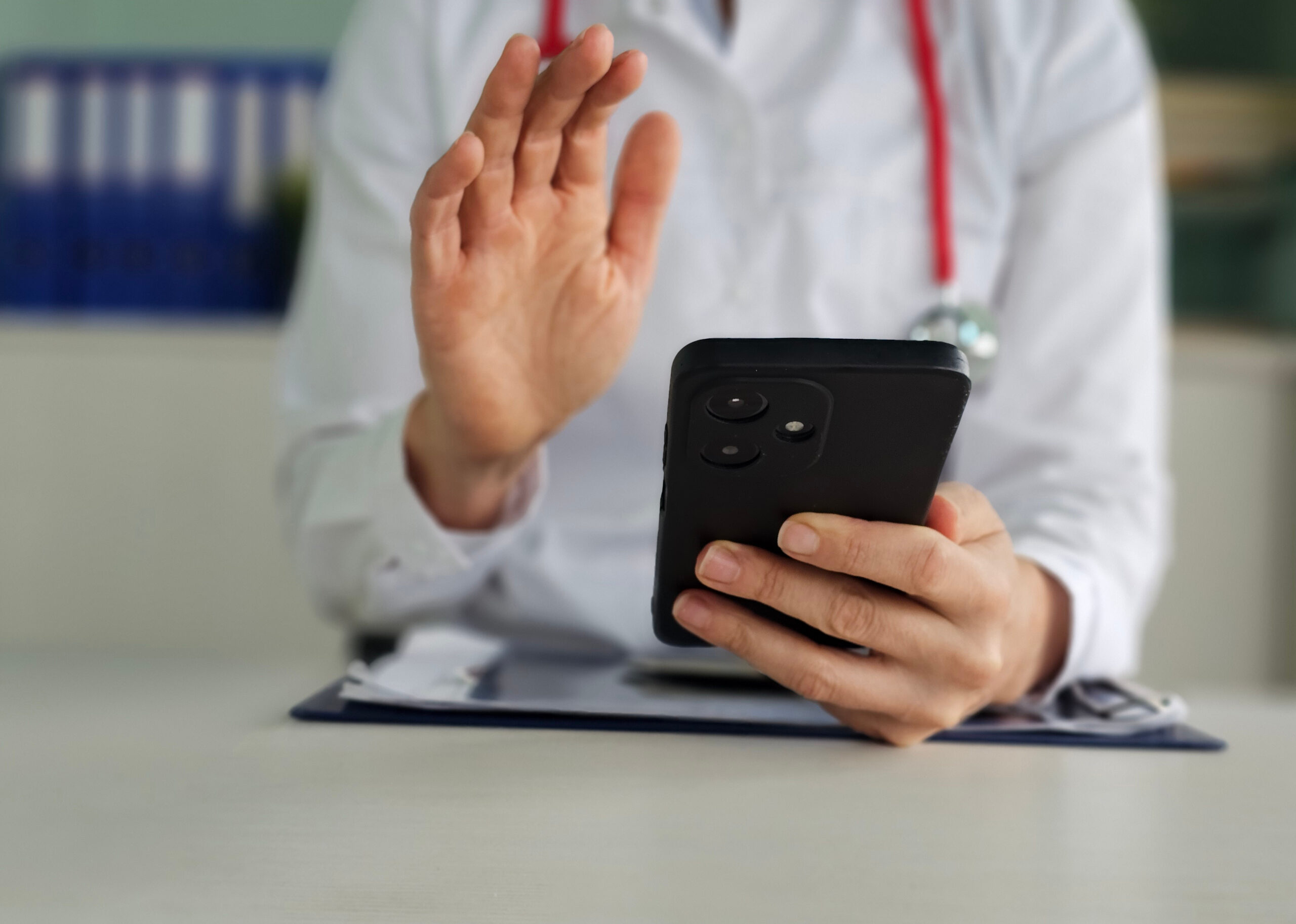 Doctor conducts telemedicine consultation while holding a smartphone in a modern medical office