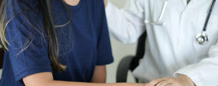 An asian psychiatrist or healthcare professional female doctor is gently holding patient hand comforting and encouragement, reassuring woman, only hands close up. Mental health care support concept.