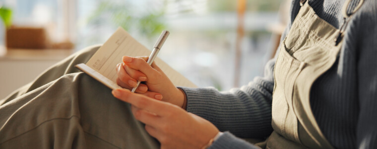Hands, person or writing in notebook in home for journal entry, schedule reminder or calendar tasks. Personal diary, woman and taking notes in apartment for to do list, inspiration and agenda planner.