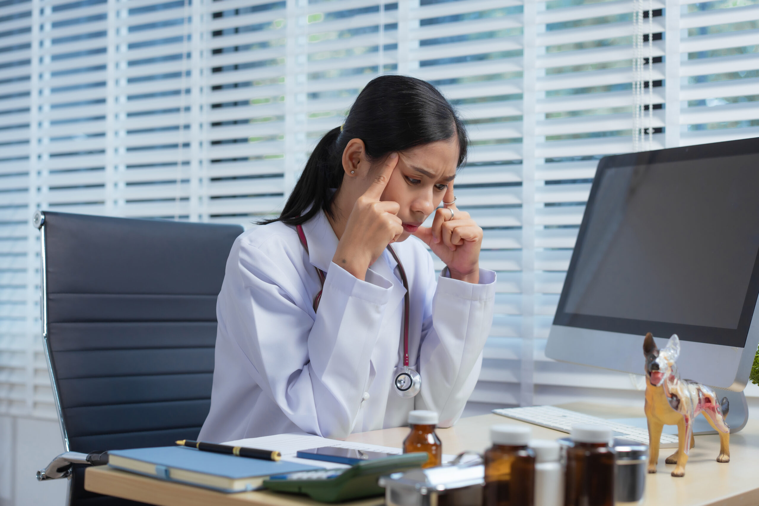 A confident Asian female veterinarian at her animal clinic feels stressed and overwhelmed by office syndrome. Despite dedication, faces moments of sadness and discouragement, struggling with setbacks
