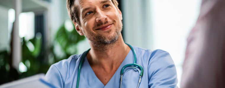Happy doctor holding medical paperwork while communicating with patient during medical appointment at hospital.