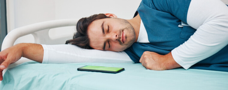 Sleeping, hospital and tired doctor with phone on bed for rest, nap and break for burnout, exhausted and fatigue. Healthcare, night shift and worker relax for medical service, wellness and stress.