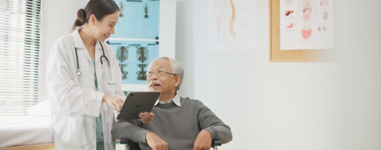 Asian female doctor using a digital tablet to explain health information to an elderly male patient, incorporating AI-assisted tools for better diagnosis, data analysis, and patient understanding.